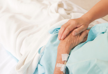 A young hand touches and holds an old wrinkled hand