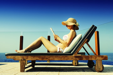 Attractive woman sunbathing while reading a magazine
