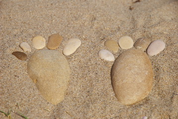 Fototapeta na wymiar stone feet on the sand