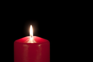 Red candle isolated against a black background