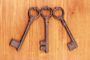 Three antique keys on wooden background