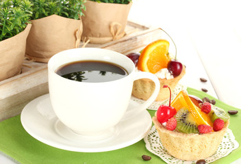 cup of coffee and sweet cakes with fruits on wooden table