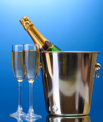 Champagne bottle in bucket with ice and glasses of champagne,