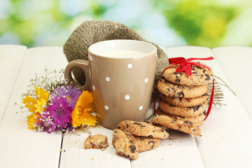 cup of milk, chocolate chips cookies with red ribbon and