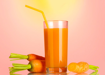 glass of carrot juice on pink-yellow background
