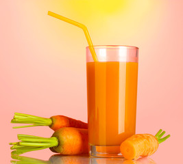 glass of carrot juice on pink-yellow background