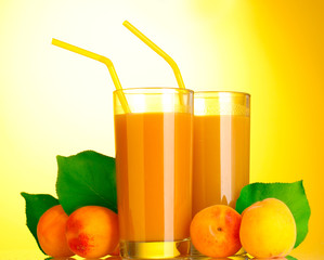 glasses of apricot juice on yellow background