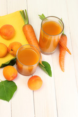 glasses of carrot and  apricot juice on white wooden table