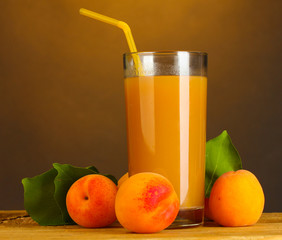 glass of apricot juice on wooden table on brown background