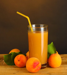 glass of apricot juice on wooden table on brown background
