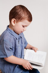 Naklejka premium Little boy looking a book