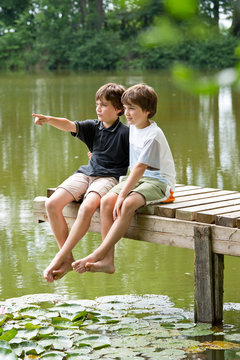 Zwei jungendliche Freunde erkunden die Umgebung am Teich