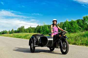 Obraz premium Pretty woman riding a motorcycle with a sidecar.