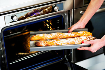 Hands of a woman holding hot baguette