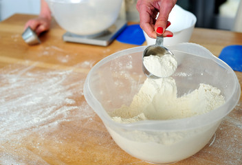 Female hand collecting flour from bowl