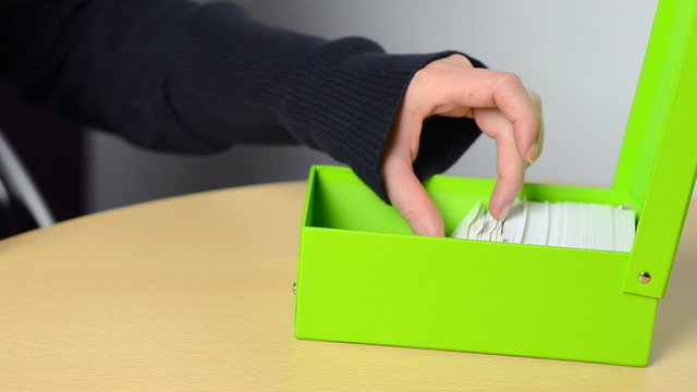 women sort some note cards in a green box