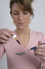 Junge Frau nimmt einen Löffel mit Medizin