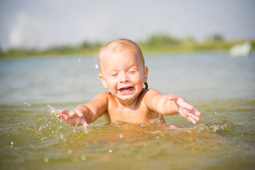 Adorable baby splashing water on lake beach