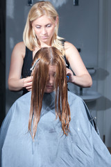 Fototapeta premium hair stylist cutting woman hair in salon
