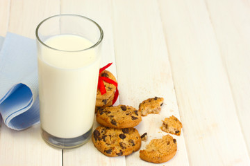 glass of milk and chocolate chips cookies with red ribbon