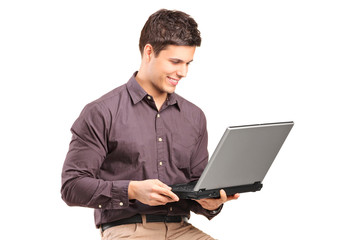 Young man sitiing on a high chair and working on a laptop