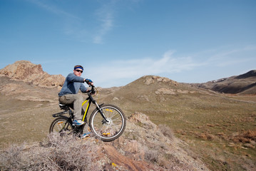Obraz premium Bicyclist in mountain terrain overcomes obstacle