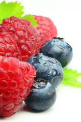Close up of raspberries and blueberries on a white background