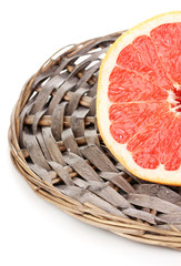 Half of ripe grapefruit on wicker mat isolated on white