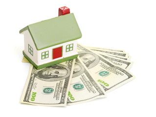 Model of a house lying on some banknotes