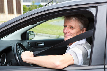 Happy Caucasian senior man fastens safety belt