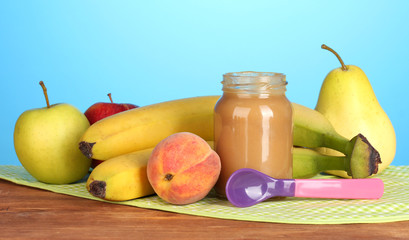 Jar with fruit baby food, spoon and fruits
