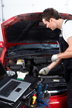Auto mechanic checking oil.