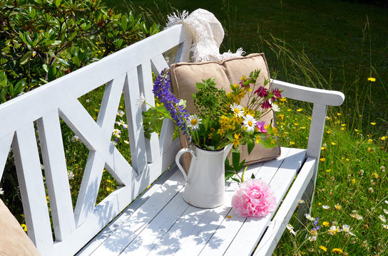 weiße Gartenbank mit Blumenstrauß