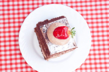 beautiful cake with strawberry on plaid fabric