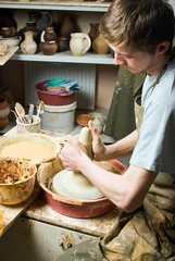 Foto op Canvas hands of a potter, creating an earthen jar on the circle © grthirteen
