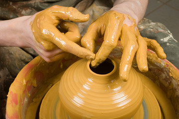 hands of a potter, creating an earthen jar on the circle