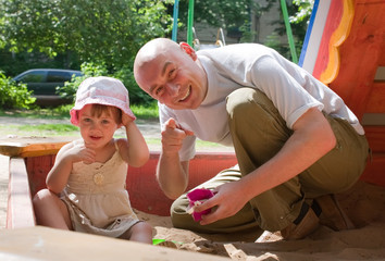 dad with  toddler  playing with sand