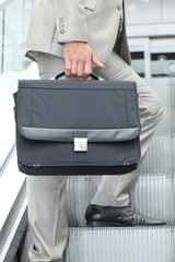 Man on an escalator holding a briefcase