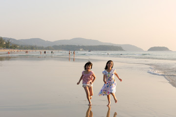 Two Asian kids running on the beach