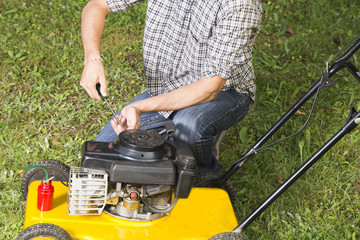 Man repairing yellow lawn mower - close up