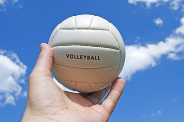volley ball in man's hand against blue sky