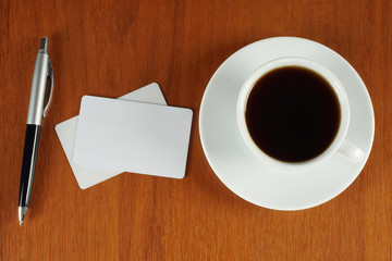 Cup of coffee with business cards and pen
