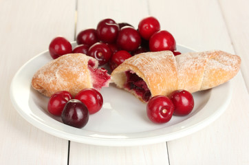 white plate with croissant and cherry