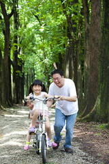 Fototapeta na wymiar Father Teaching daughter to riding bicycle