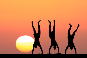 Three acrobats on the sunset background