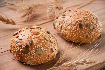 Close-up of two freshly baked buns and wheat ears