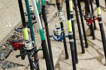 Rods with reels covered with drops of water stand on ground
