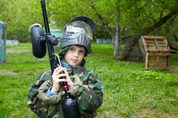 Boy in camouflage suit stands against the paintball area