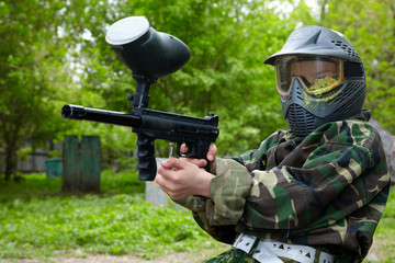 Paintball player in camouflage uniform and protective mask