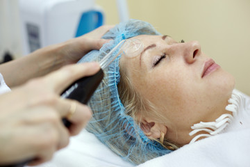 Fototapeta na wymiar Woman in beauty salon gets face skin treatment